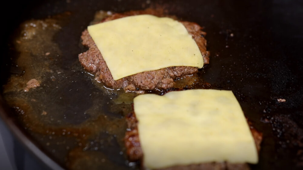 This_image_shows_cheese_being_added_to_burger_patty