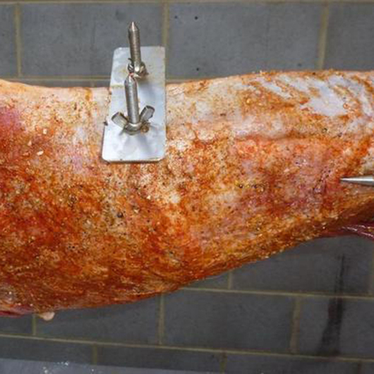 Back brace attachment securing a whole animal on a spit rotisserie for even cooking