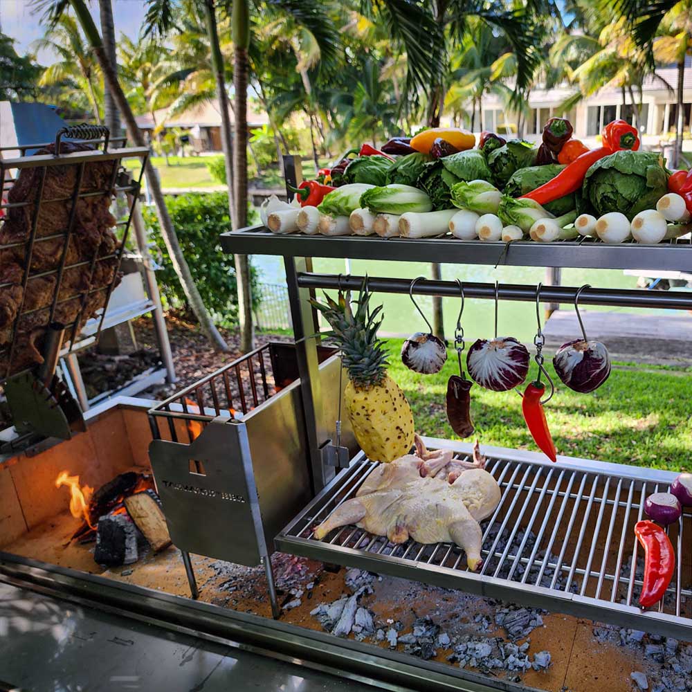 TAGWOOD Argentine parrilla grill with hanging vegetables and whole chicken over wood fire