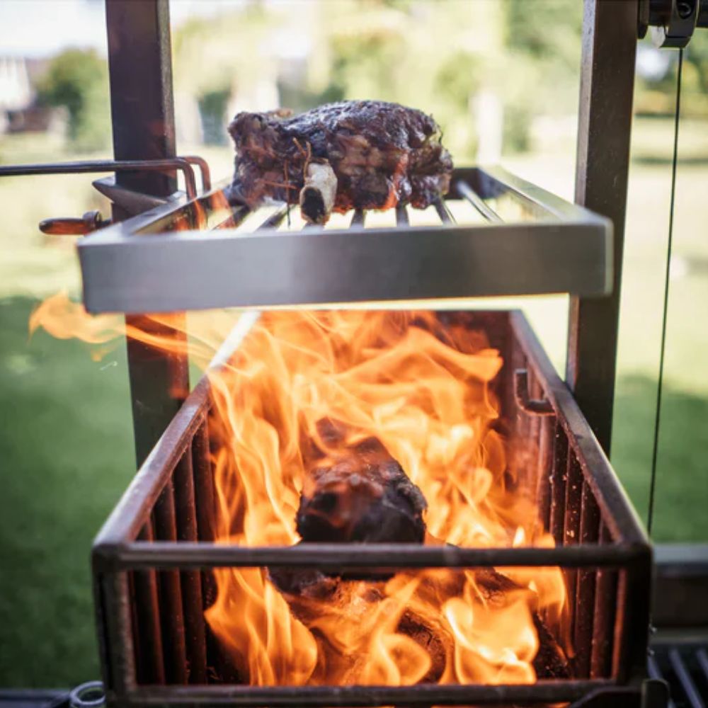 Tagwood height adjustable secondary grate cooking steak above wood fire on parrilla grill