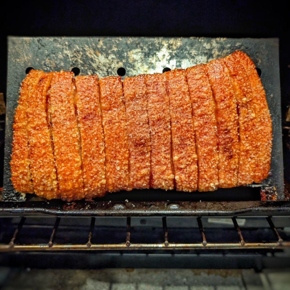 Boomas Pork Belly Stand holding crispy roasted pork belly with golden crackling inside an oven, designed for even cooking and crunchy crackle results.
