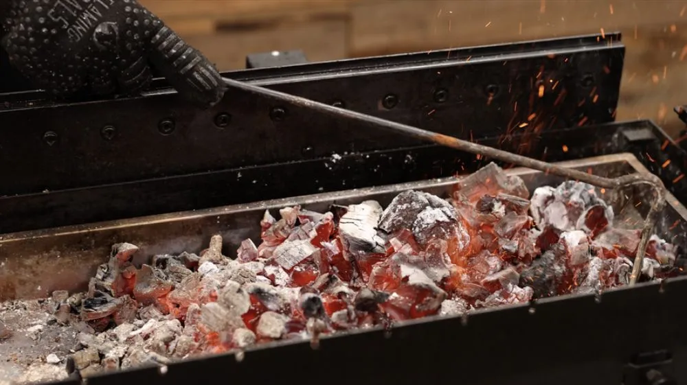 Burk being used to move lit charcoal on a spit rotisserie