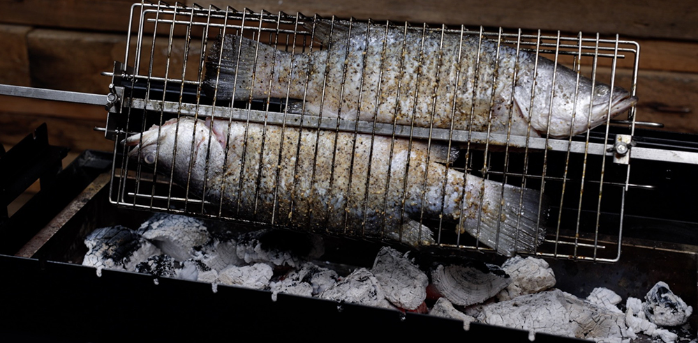This image shows Barramundi in the rotisserie basket cooked in Cyprus spit