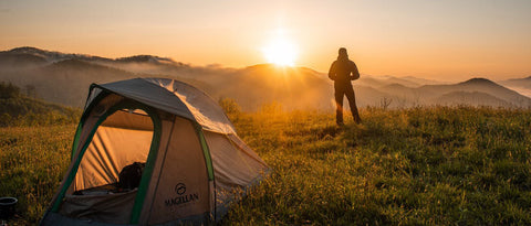 This image shows man watching a beautiful sunset during camping