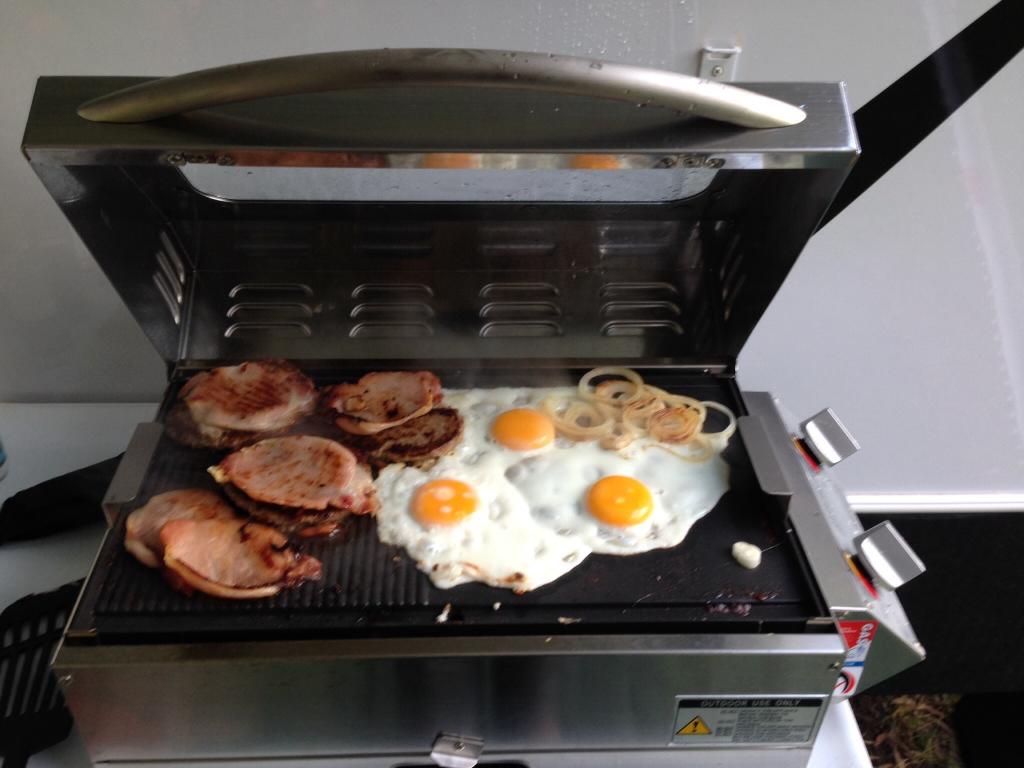The perfect caravan Breakfast, This image show eggs, bacon and onions being cooked in a sizzler deluxe caravan BBQ