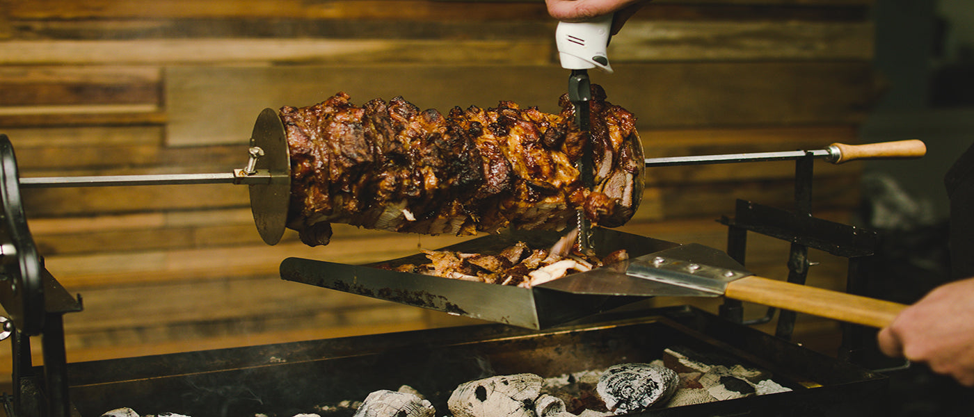 This image shows a man carving the chicken gyros