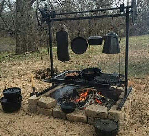 This is a picture of a wide range of cast iron cookware hanging above a firepit. This is a great setup and well equiped
