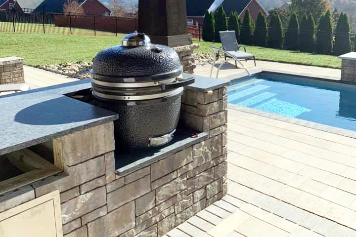 This in a picture on an SNS Grills, kamado ceramic BBQ smoker setup next to a swimming pool in a backyard