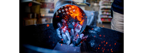 This_image_shows_charcoal_chimney_with_lit_charcoal_being_poured_in_the_Weber_kettle