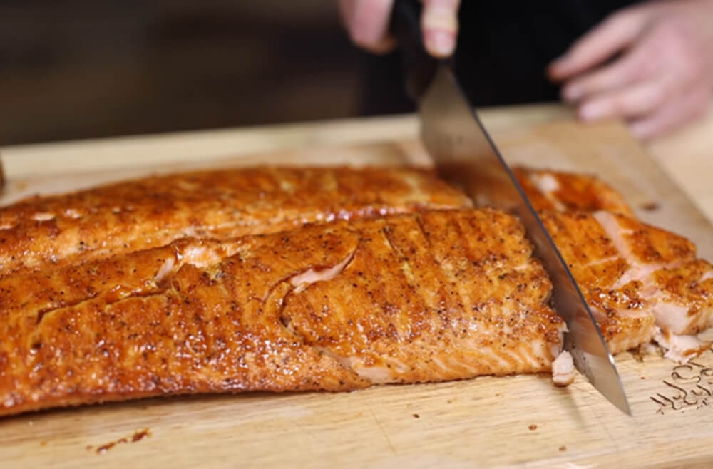 This image shows delicious salmon glazed with Lanes Pineapple Chipotle sauce to the salmon is being sliced