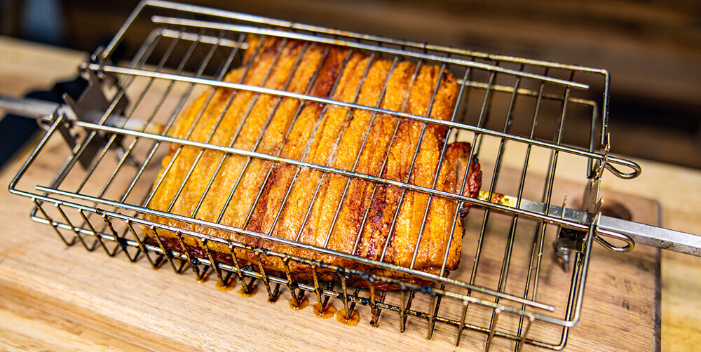 This image shows the pork belly being remove in the kettle rotisserie