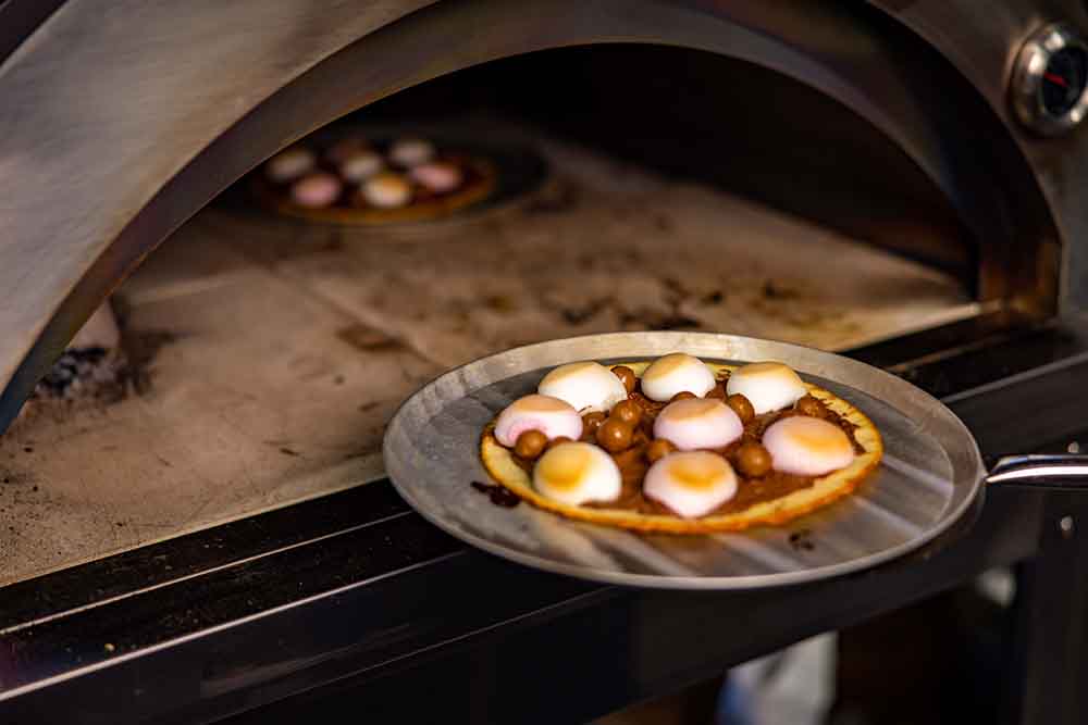 This_image_shows_dessert_pizza_being_cooked_on_wood_fired_pizza_oven
