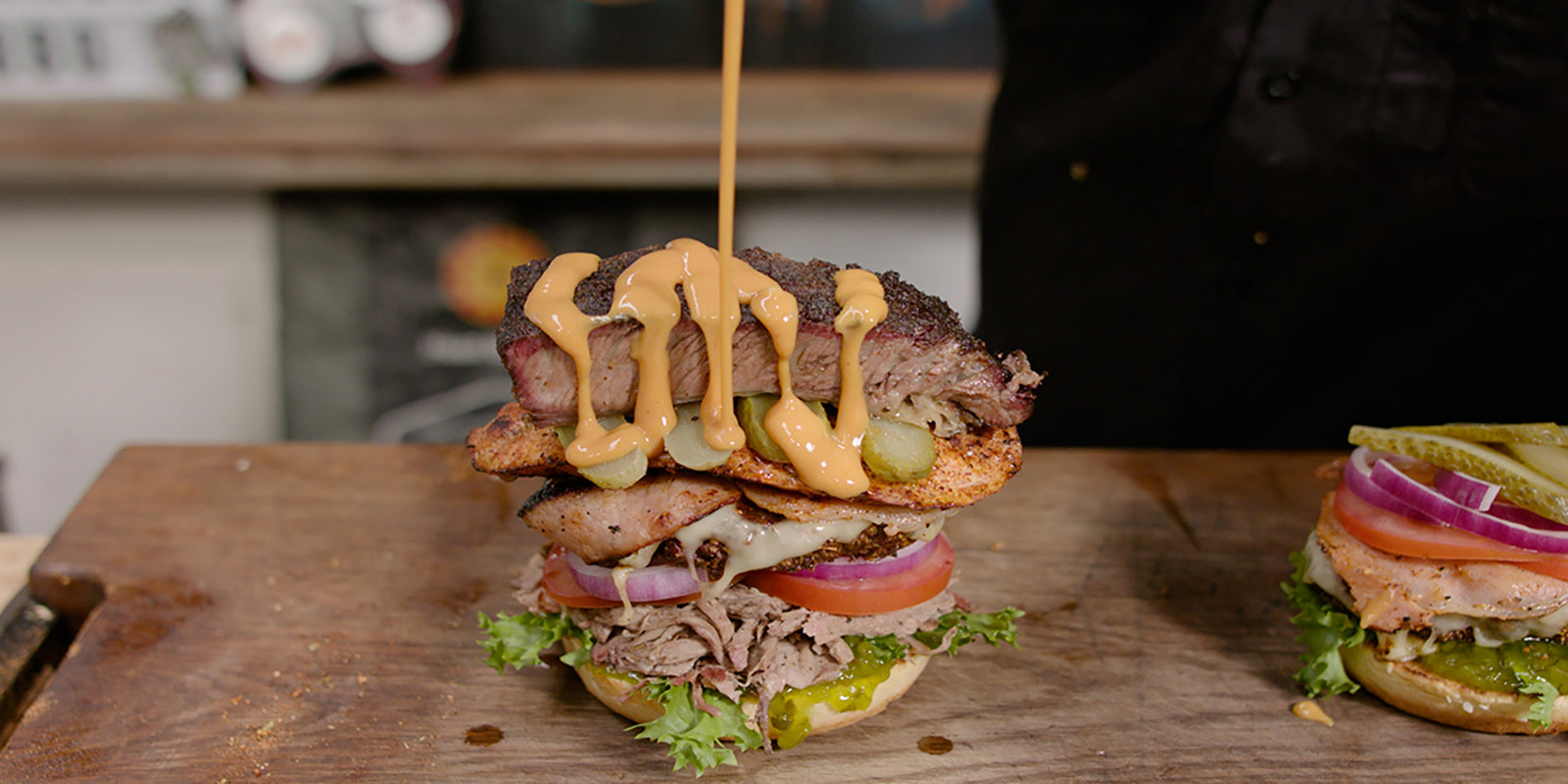 This image shows a man adding burger sauce to the burger stacker