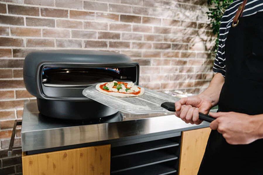 Loading a pizza in an Everdure Pizza Oven