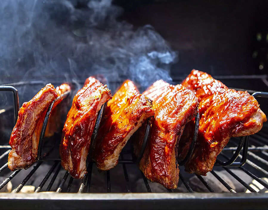 bbq rib rack holding glazed pork ribs upright on grill with smoke for even cooking