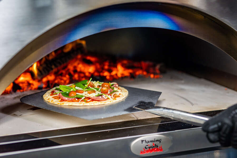 This_image_shows_a_pizza_peel_being_used_in_the_oven_for_easy_turning