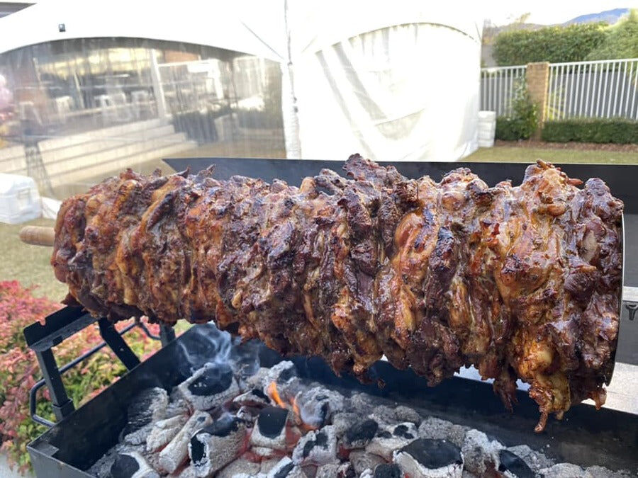 Gyros disc holding stacked meat rotating over charcoal on a spit rotisserie