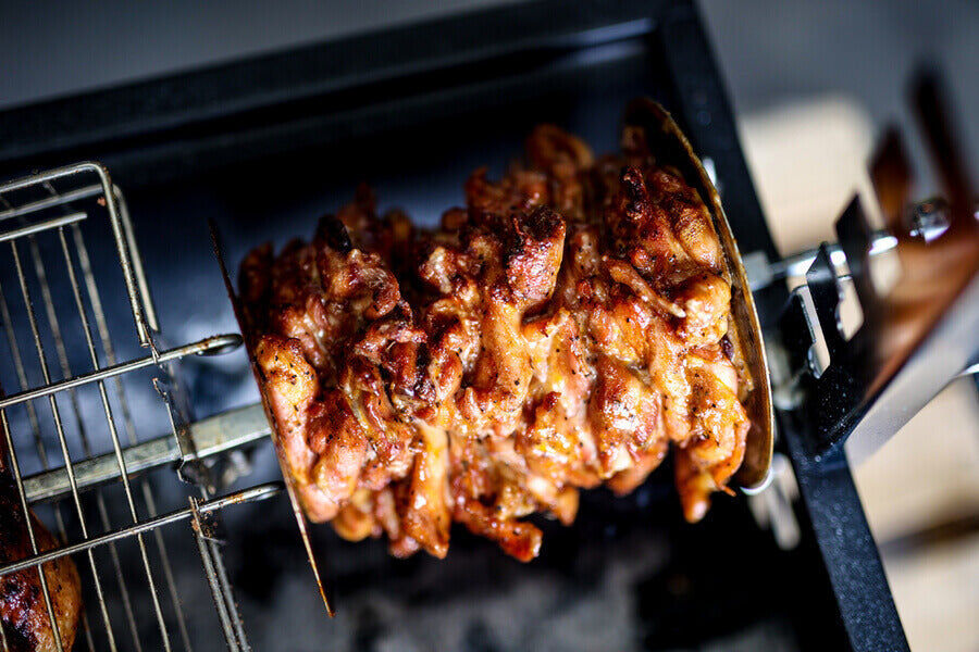 Gyros disc holding stacked marinated chicken cooking on a spit rotisserie