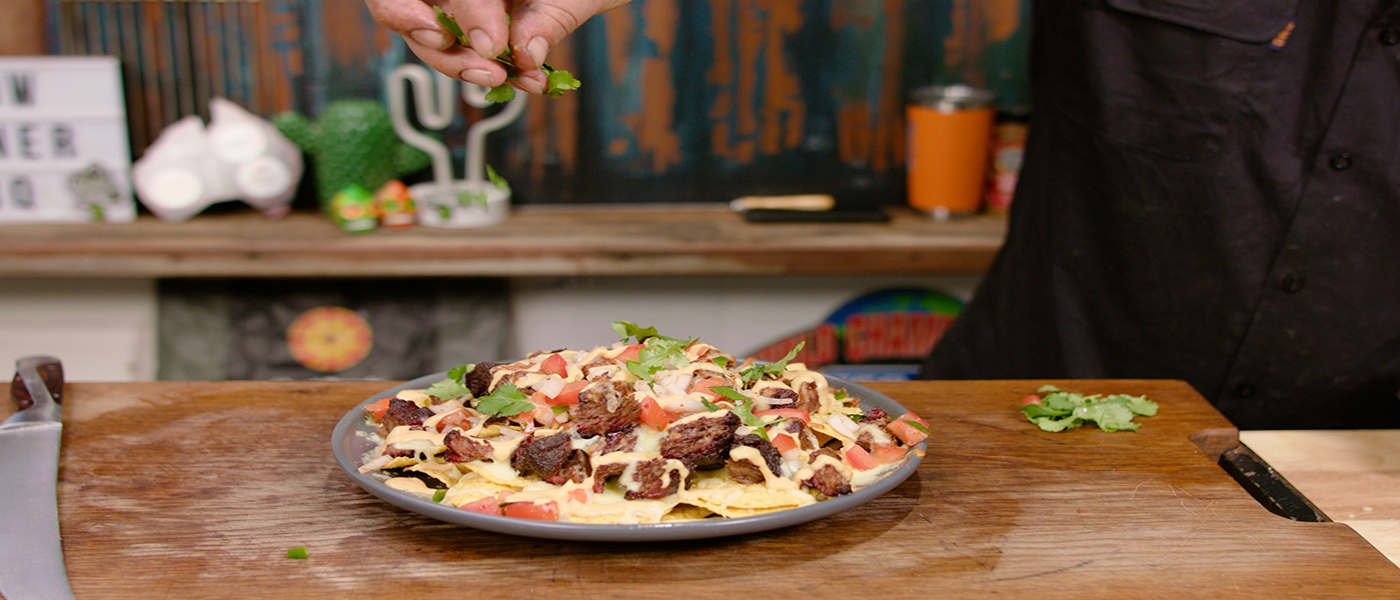 This image shows a man adding herbs to the Beef Nachos