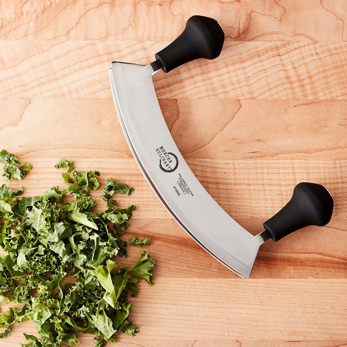 This image shows the Mercer 8" Double Blade Mezzaluna Herb Cutter laying next to the freshly chopped Parsley
