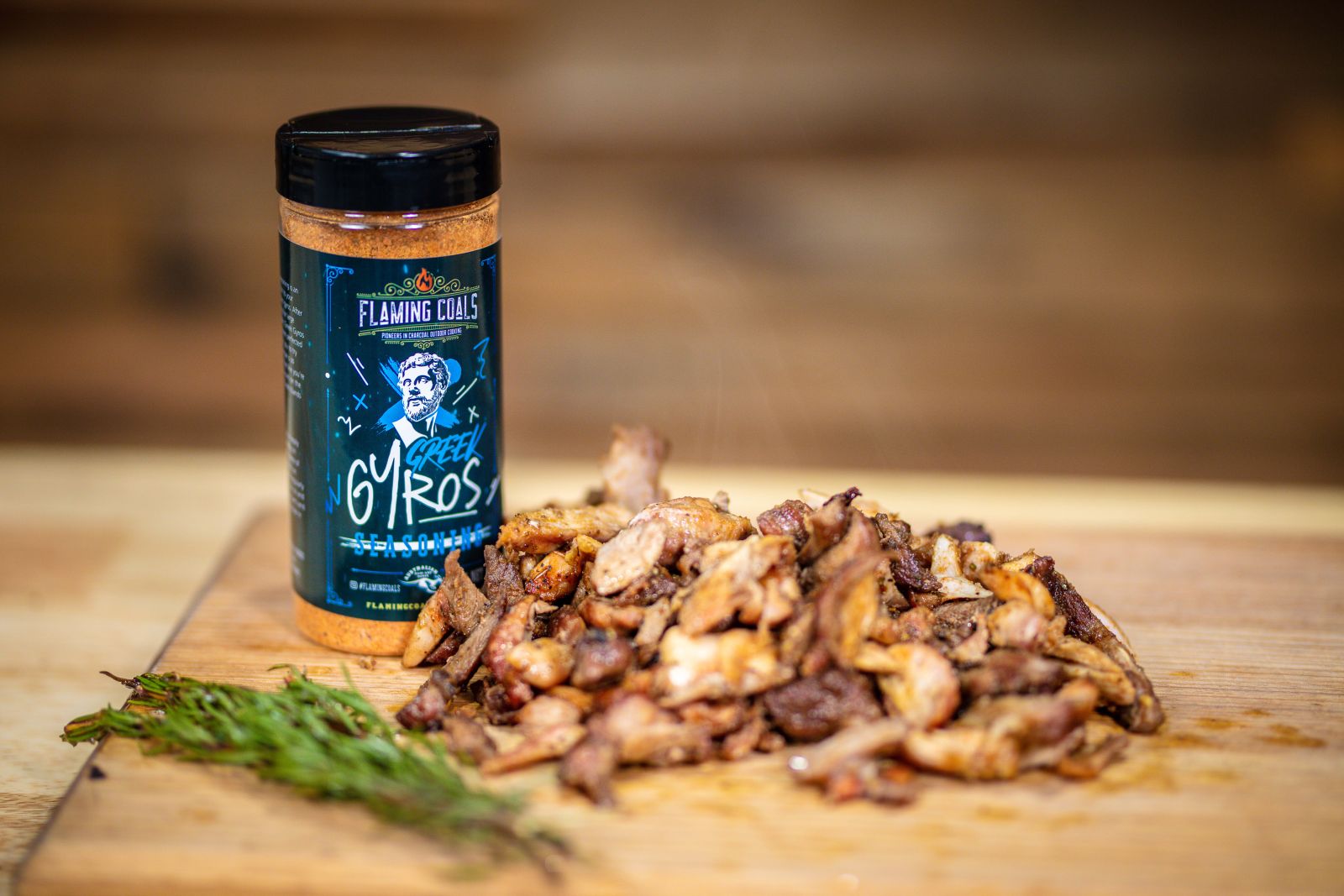 Flaming Coals Greek Gyros Seasoning with freshly cooked sliced gyro meat on a wooden board.
