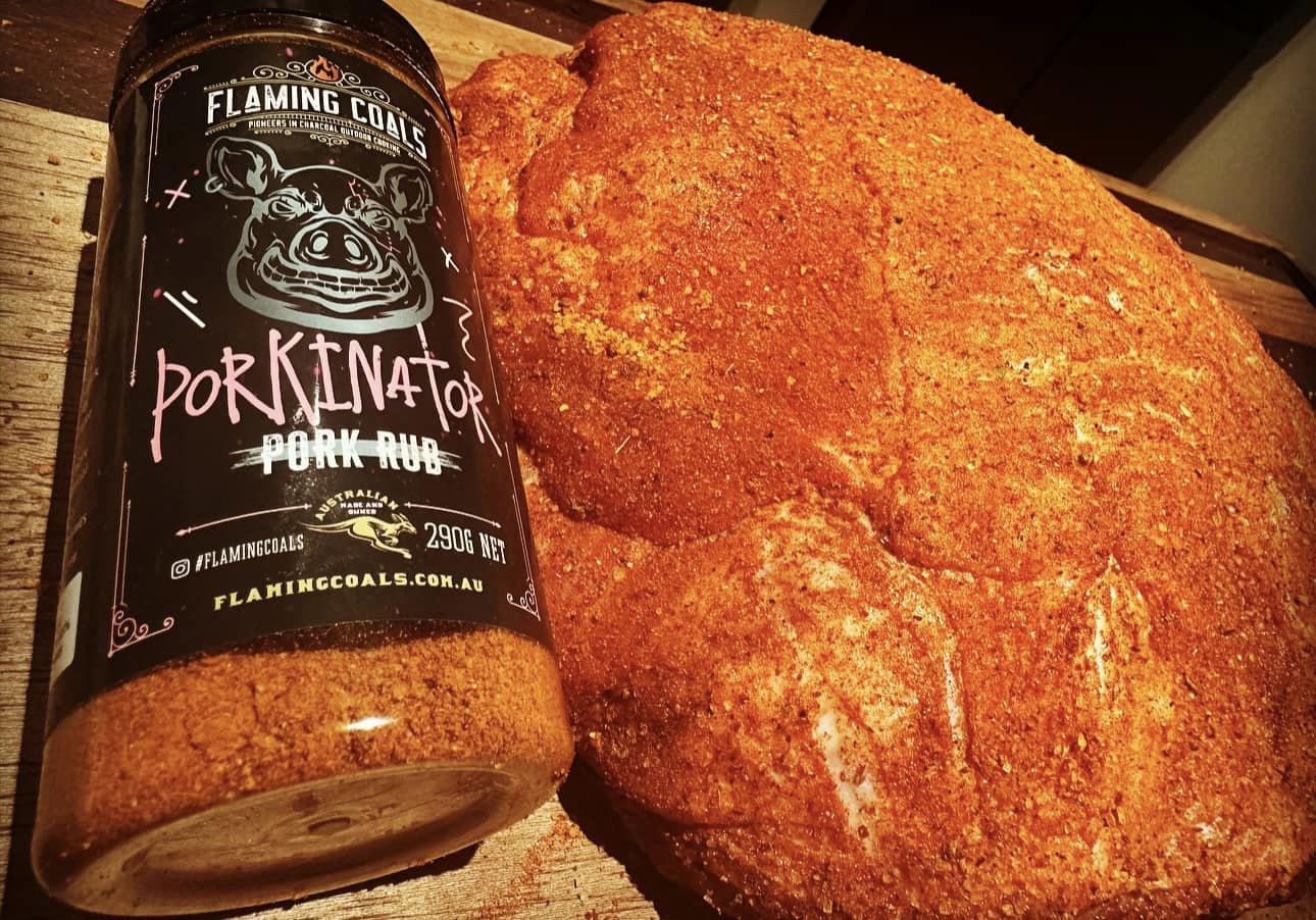 Flaming Coals Porkinator Pork Rub with a pork shoulder coated in seasoning, ready for roasting or smoking.