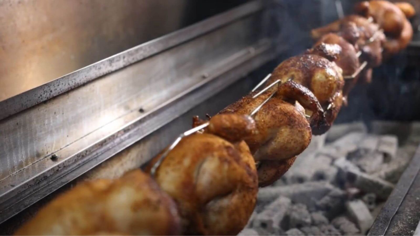 Spit rotisserie cooking meat over charcoal