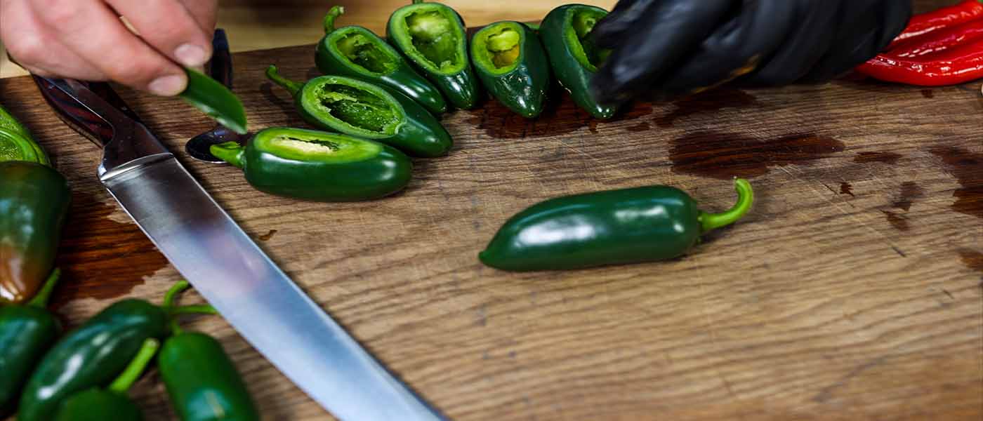 This image shows a man scalloping the top layer of the jalapeños.