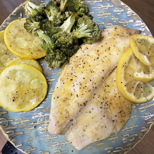 This image show a plate of dinner with fish and vegetables seasoned with LANES Sweet Lemon Pepper Rub