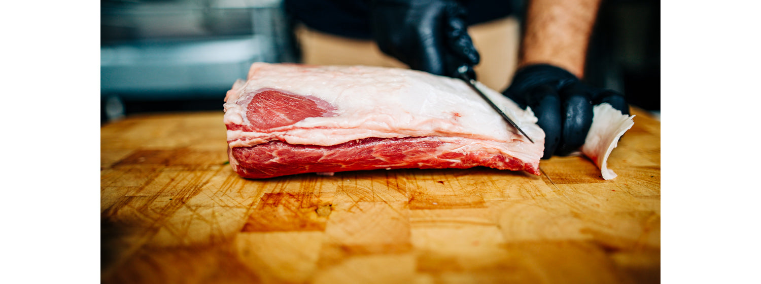 This image shows a man trimming the fat of lambs. 