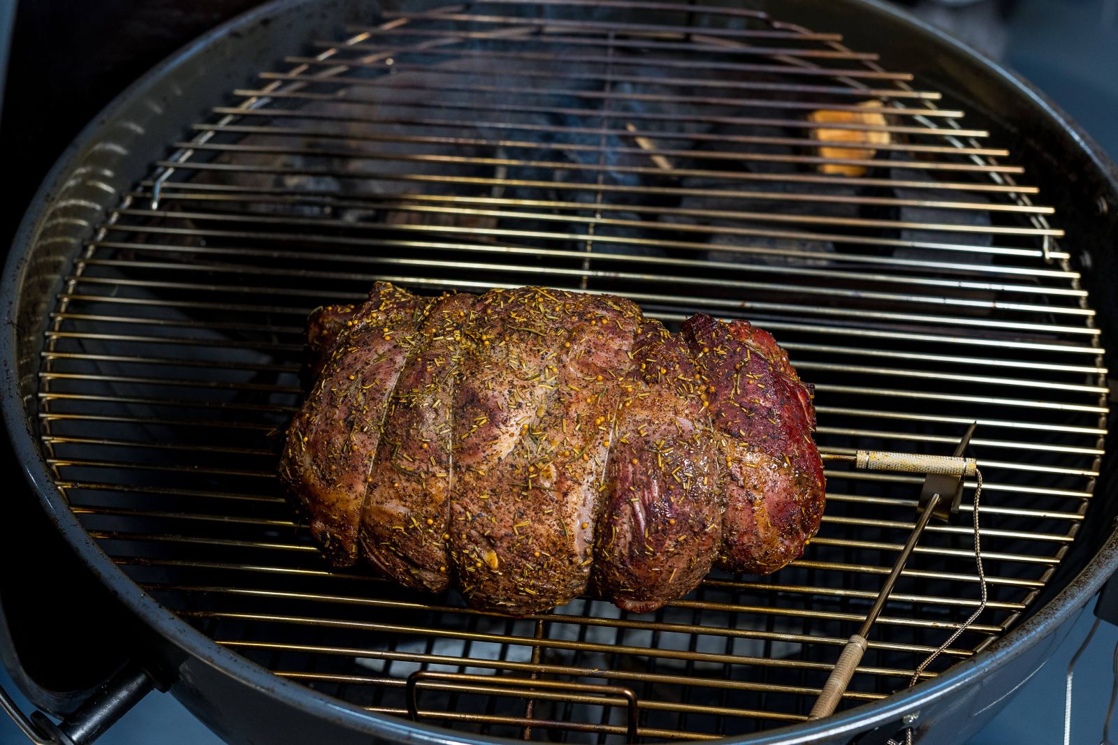 Herb-seasoned roast cooking low and slow on an SNS grill with charcoal baskets for even heat and perfect smoke flavour.