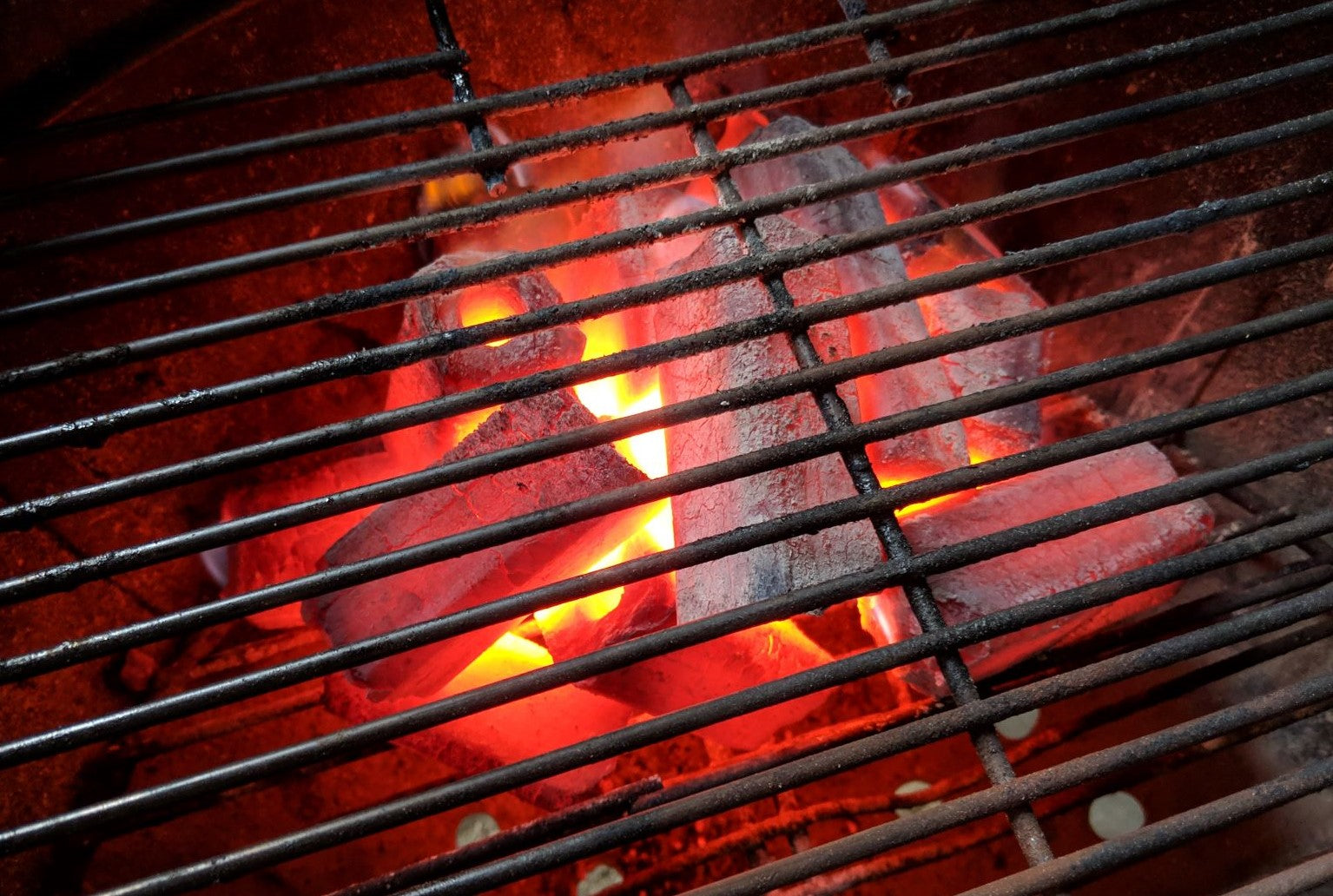 Image show long lasting glowing Hot White Charcoal Briquettes in a weber kettle