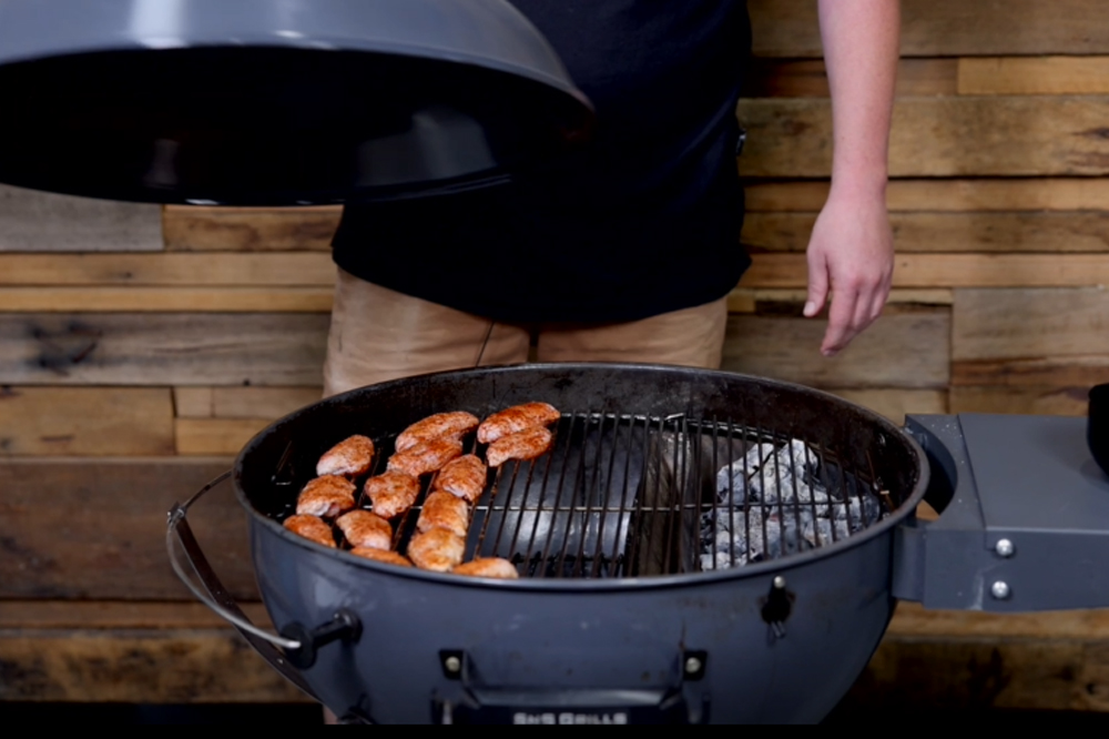 This_image_shows_chicken_wings_being_placed_on_SNS_kettle_grill