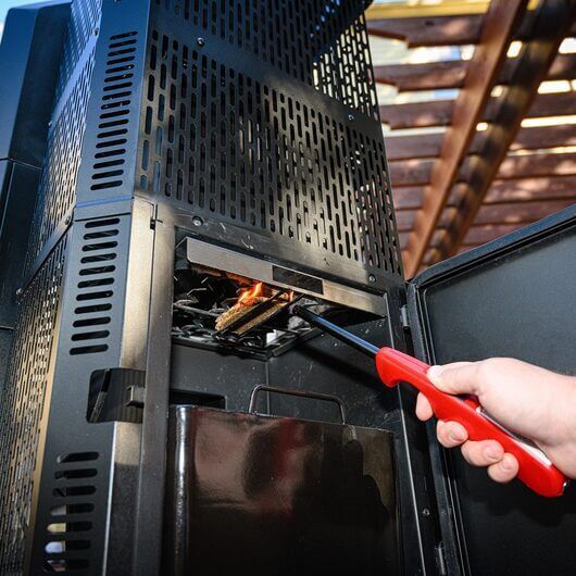 Lighting the charcoal hopper of a Masterbuilt Gravity Feed Smoker with a fire starter.