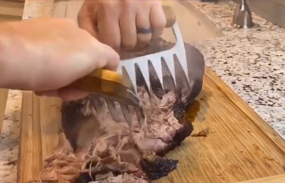 This image shows the metal meat shredding claws being used my a chef to make pulled pork