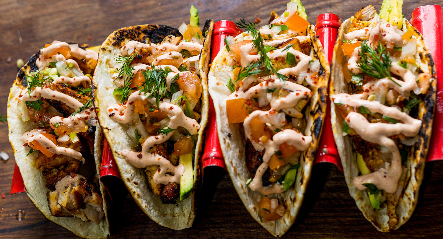 Leftover BBQ meat tacos filled with charred grilled meat, fresh tomato salsa, herbs, and drizzled with creamy sauce on toasted tortillas.