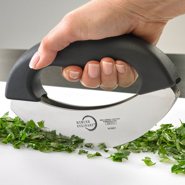 This picture shows the Mezzaluna Herb Chopper being used to finely shop some parcley