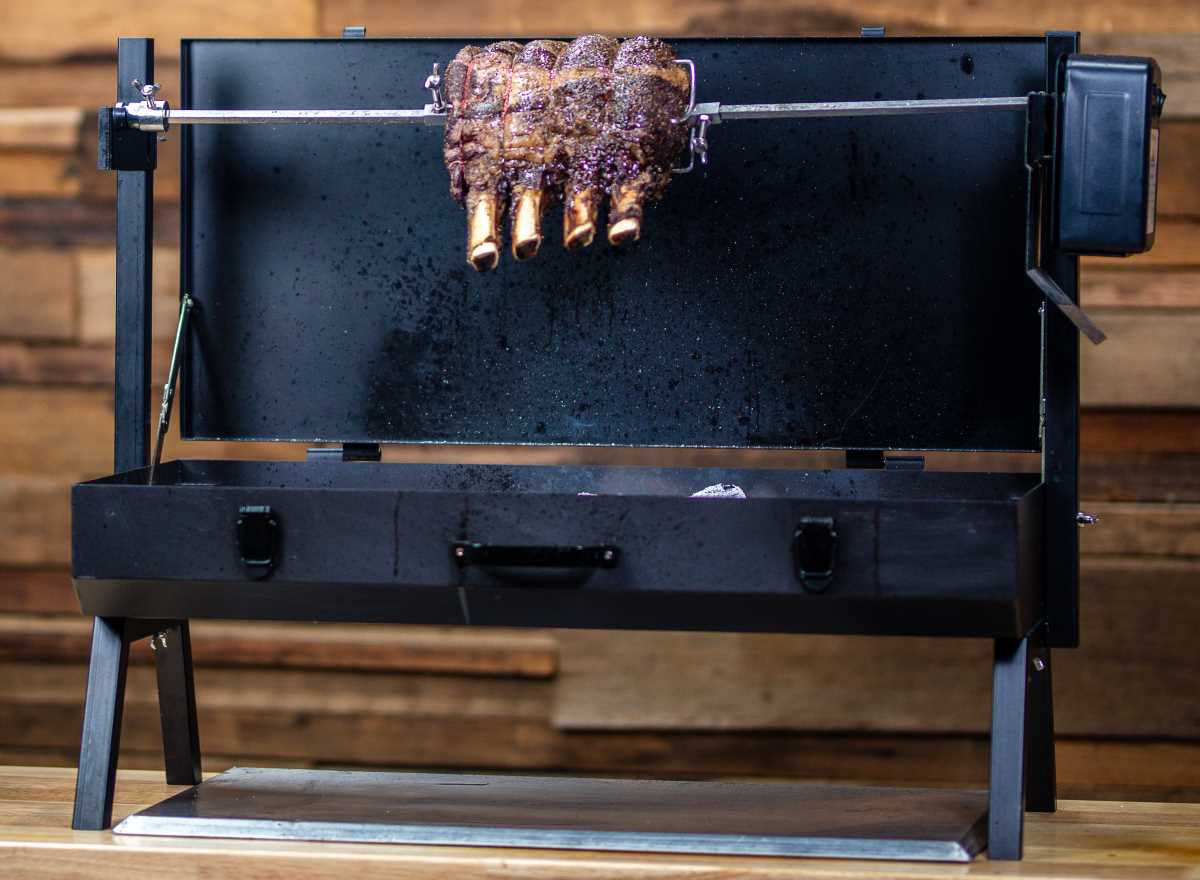 This is a picture on a mini spit roaster cooking beef ribs over charcoal on a bench top