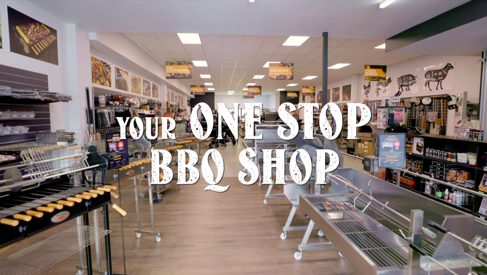 BBQ Spit Rotisseries showroom filled with grills, rotisseries, BBQ tools, and accessories, showcasing a well-organized layout. 'Your One Stop BBQ Shop