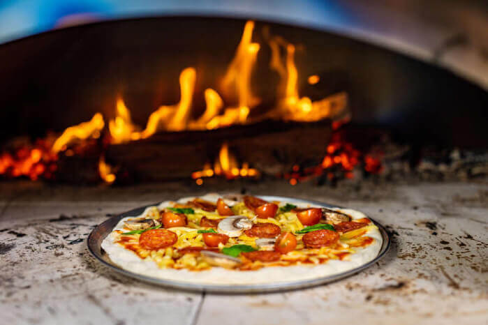 This image shows a Pizza on a Woodfired Pizza Oven