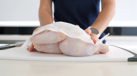 Whole chicken for roasting being pat dry