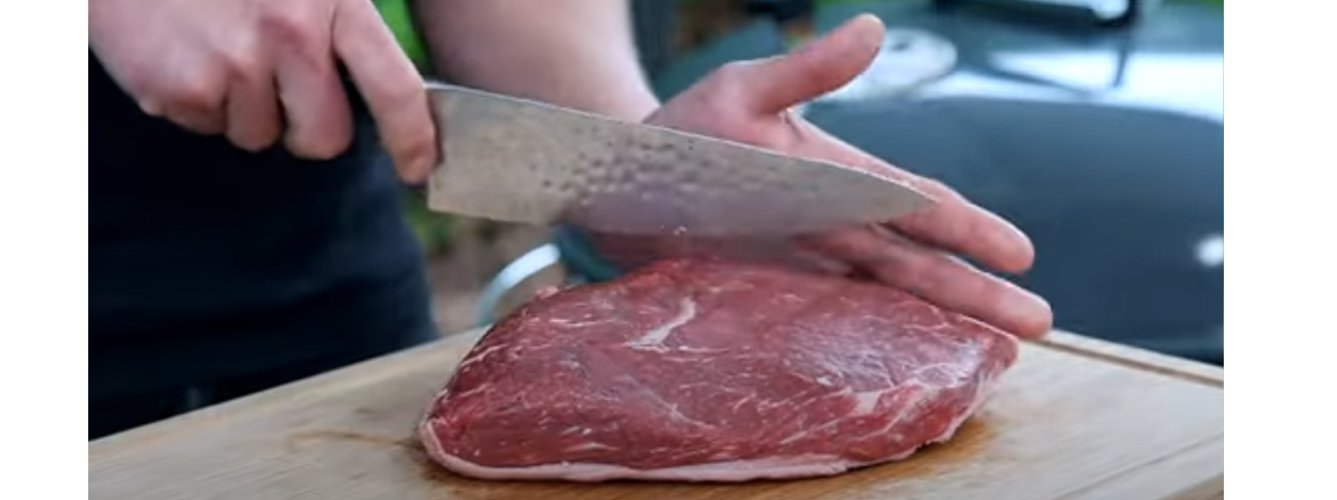 This image shows a man cutting the picanha steak