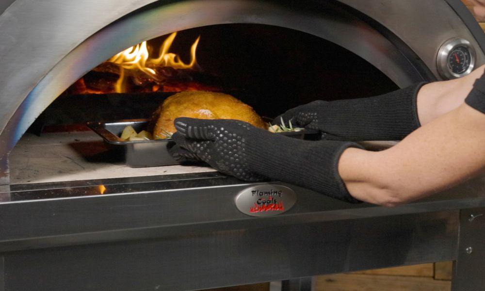 This image shows whole chicken being placed on a wood fired pizza oven