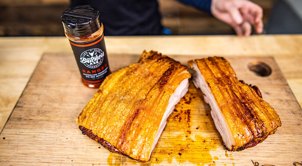 Crispy pork crackling sliced on a wooden board with Butcher’s Axe seasoning beside it.