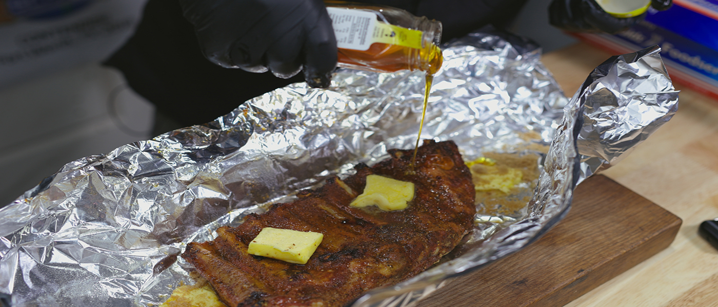 This image shows a man wrapping the pork ribs with honey, butter and sugar
