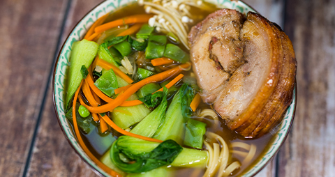 This image shows a cooked pork loin with soup and vegetables