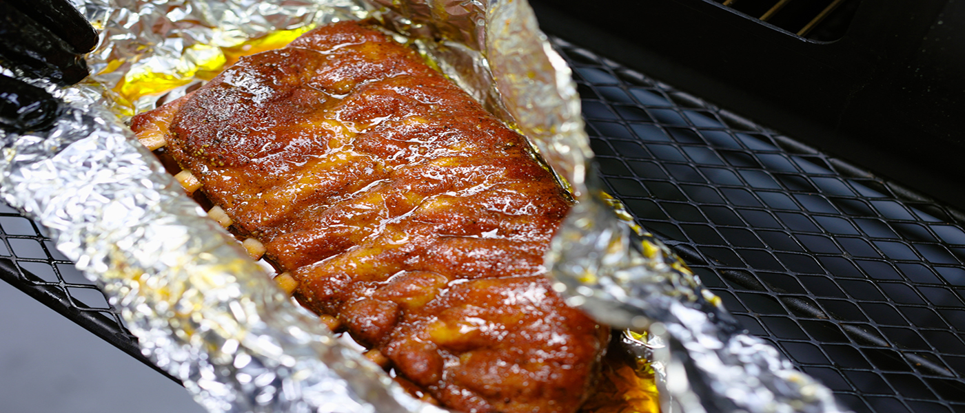 This image shows a the wrapped pork ribs placed on Flaming Coals Offset Smoker