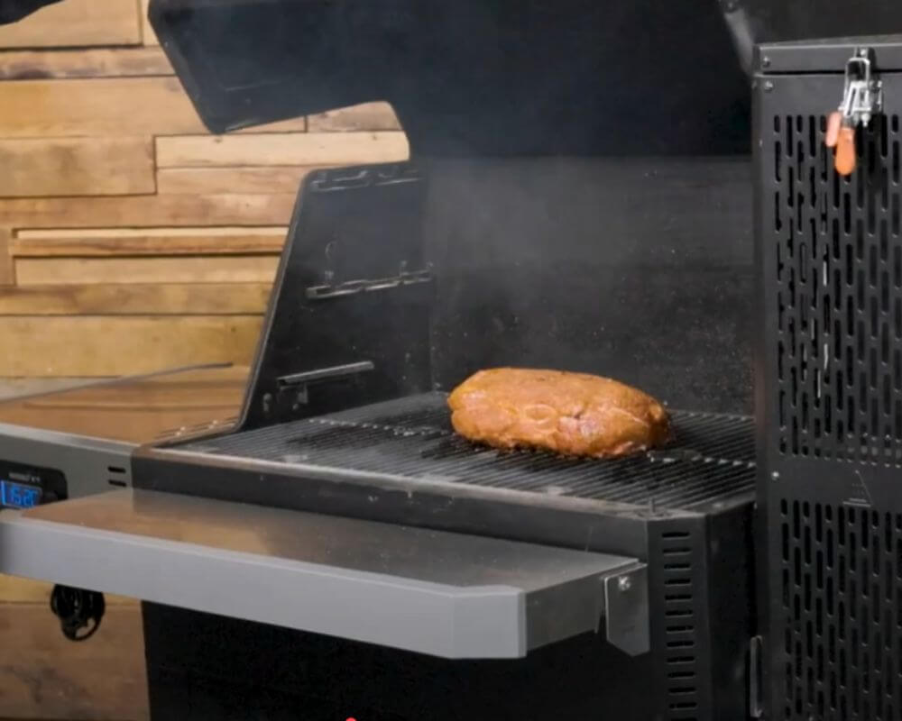 Seasoned pork shoulder smoking inside a Masterbuilt Gravity Feed Smoker at 300°F.