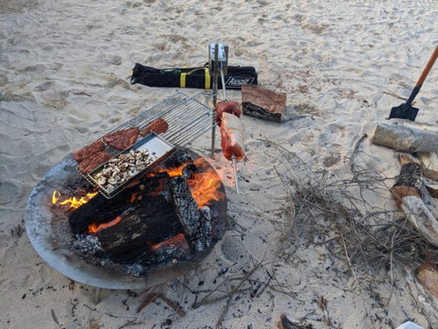 This image shows veggies and meat being cooked in the portable camping spit during camping