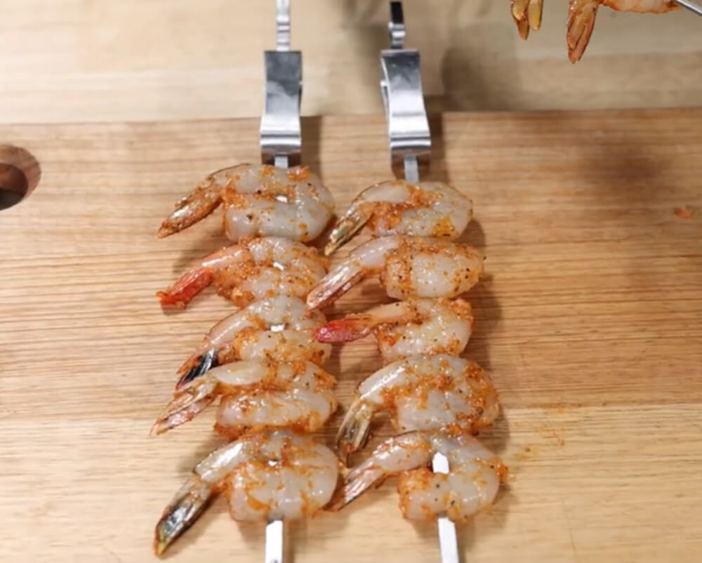 This image shows prawns on kebab skewers